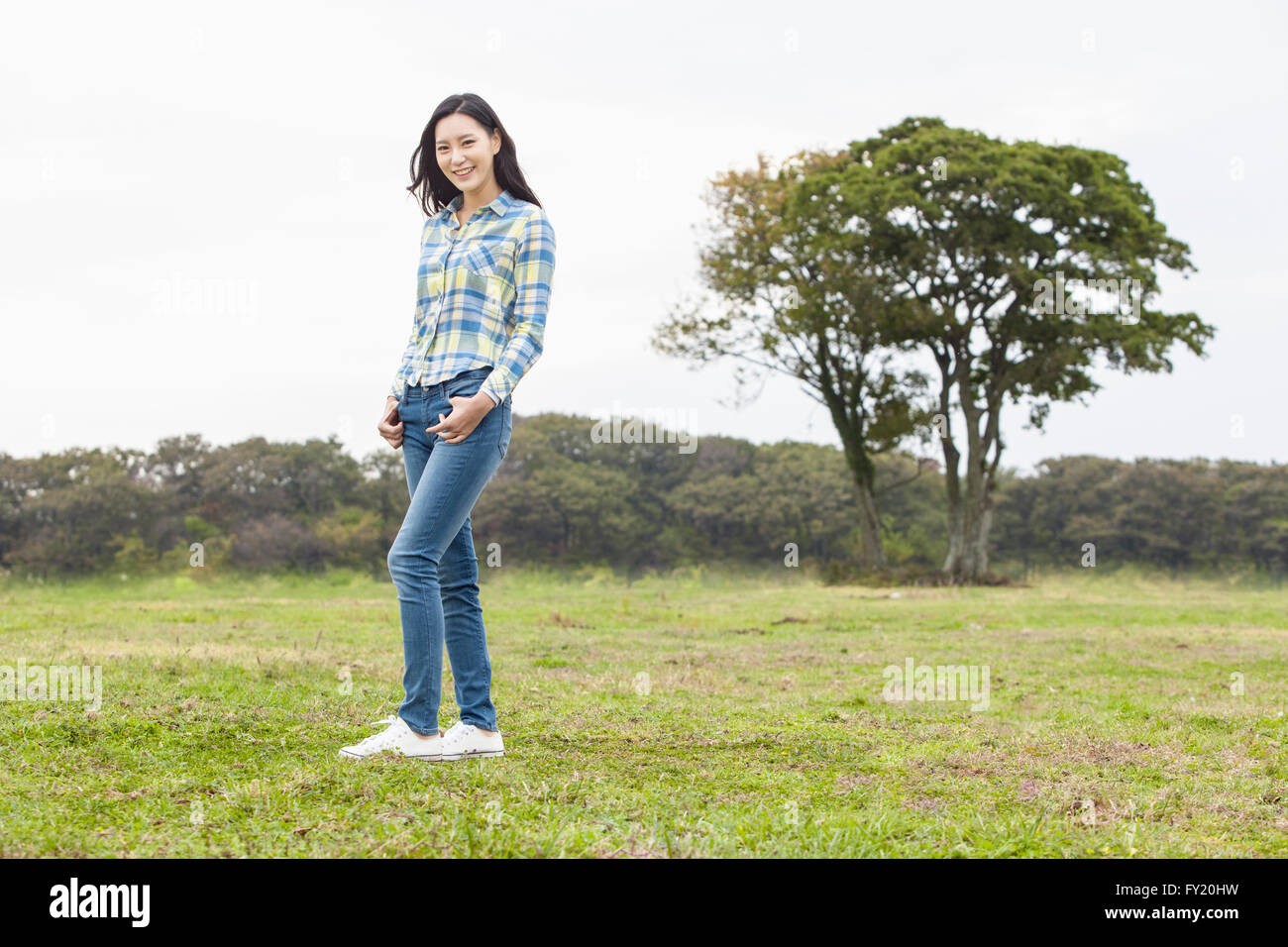 Donna in piedi sul campo verde e sorridente Foto Stock