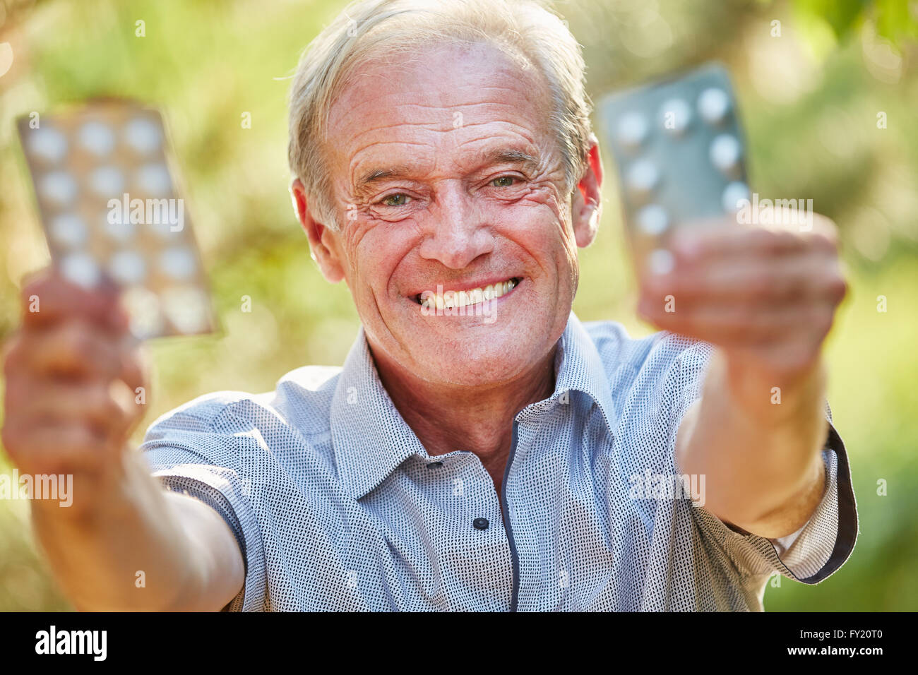 Senior uomo detiene il medicamento con gioia nella natura Foto Stock