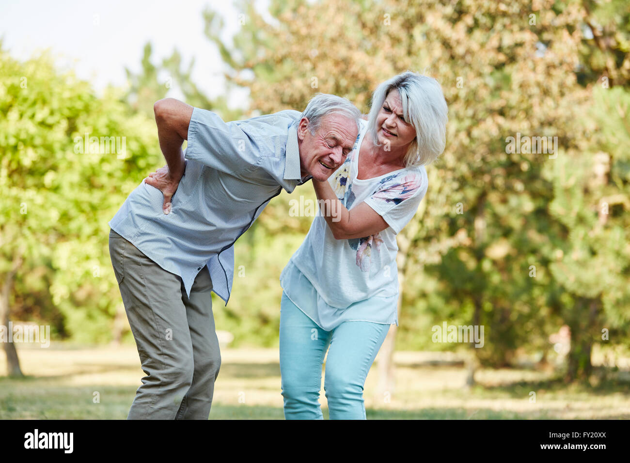 La donna aiuta l uomo vecchio con dolore alla schiena nel parco in estate Foto Stock