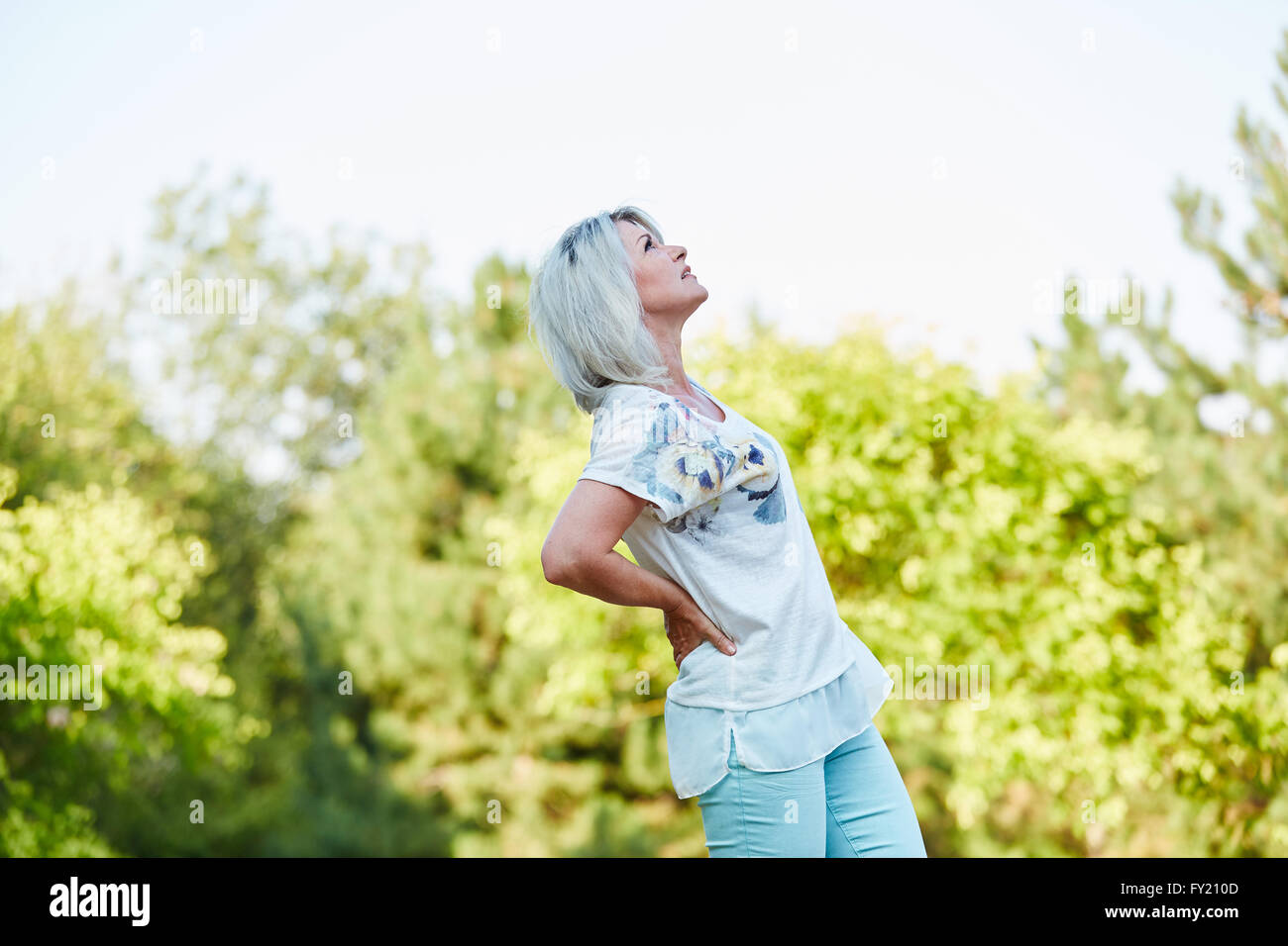 Senior donna avente lombaggine dolore nella natura in estate Foto Stock