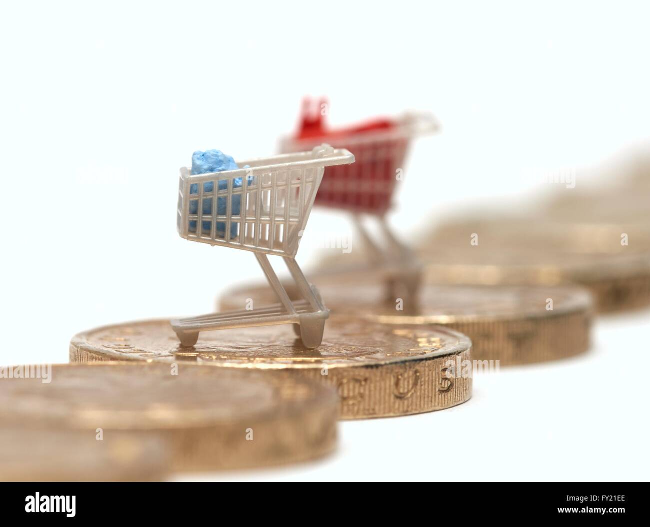 Due supermarket shopping trollies su un British pound coin Foto Stock