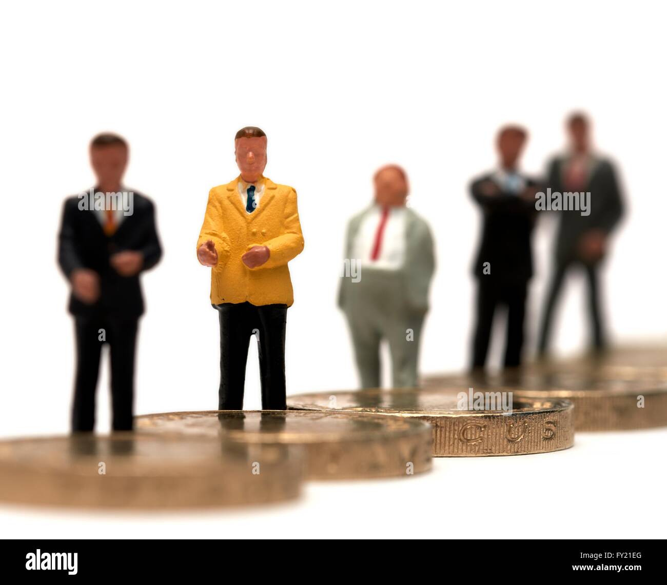 Un gruppo di figurine in miniatura di uomini di affari in piedi su alcuni britannici una libbra di monete Foto Stock