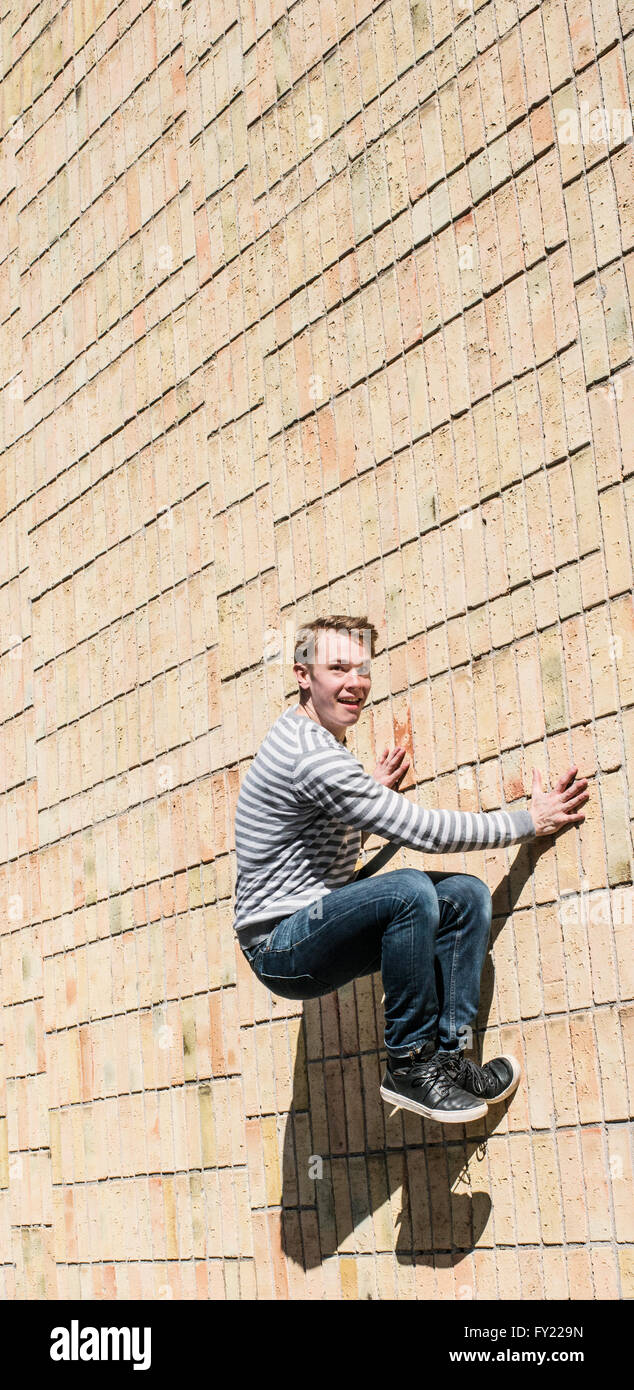 Giovane uomo che fa parkour saltare sul muro di mattoni, Svezia Foto Stock