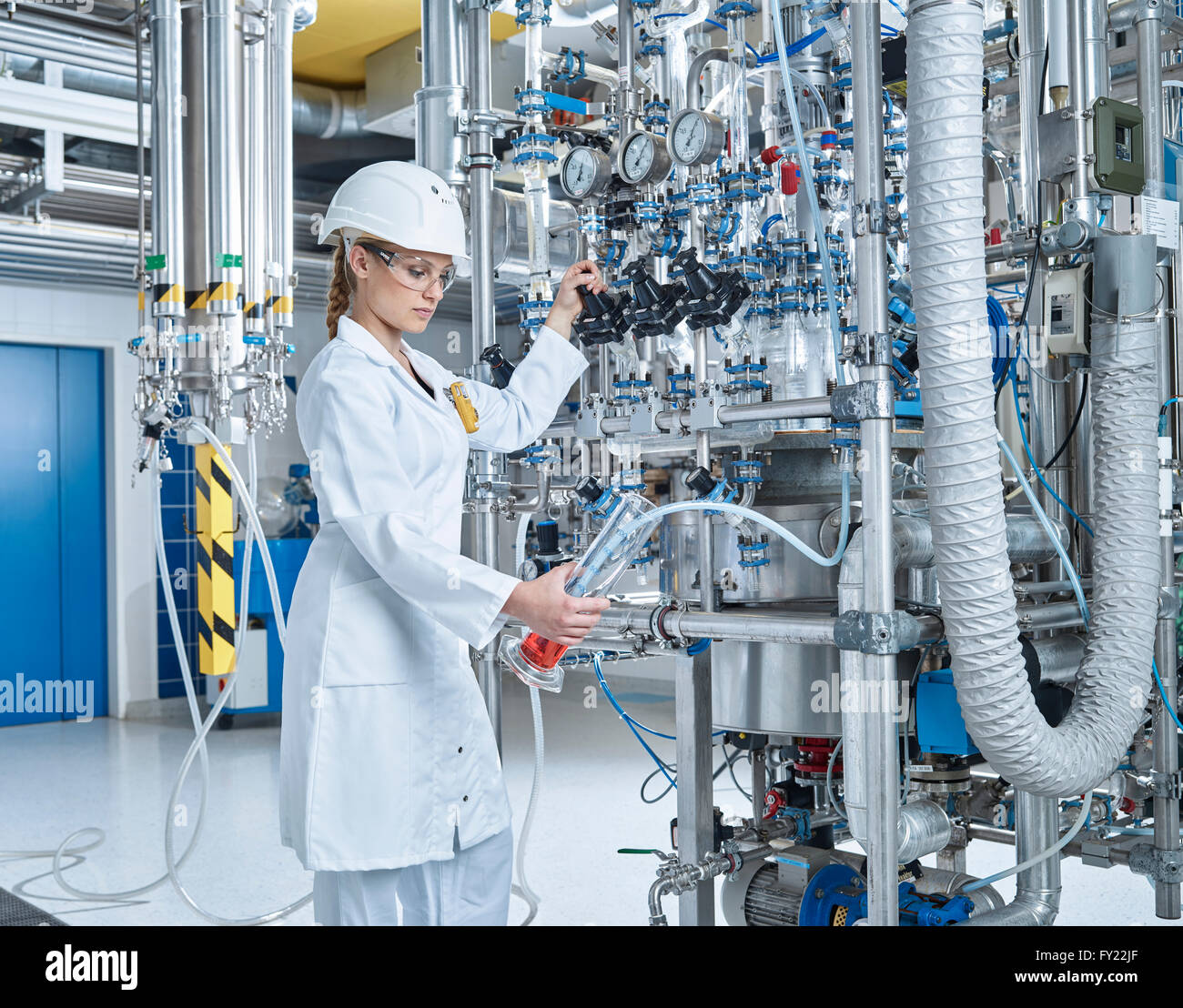 Femmina assistente di laboratorio, 20-25 anni, farmacia il riempimento di un recipiente con un liquido rosso in un laboratorio, Wattens, Innsbruck Land Tirolo Foto Stock