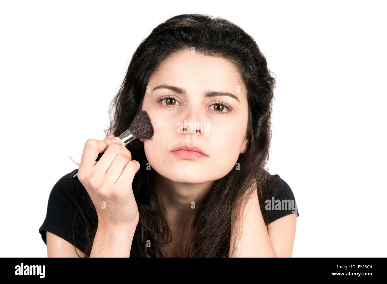 Giovane donna utilizza una spazzola cosmetica per applicare blush trucco per il viso. Foto Stock