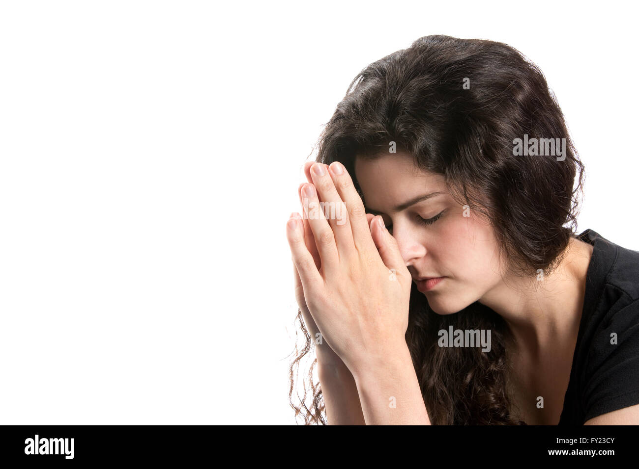 Giovane donna che prega con la testa piegata e le mani insieme. Foto Stock