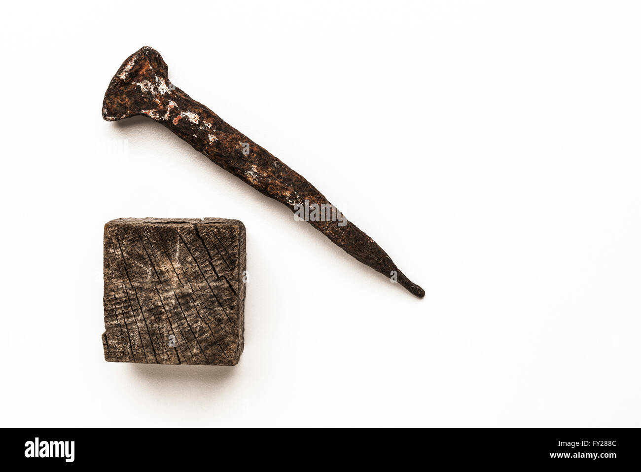 Close-up del vecchio chiodo arrugginito e vecchio cubo di legno isolato su sfondo bianco Foto Stock