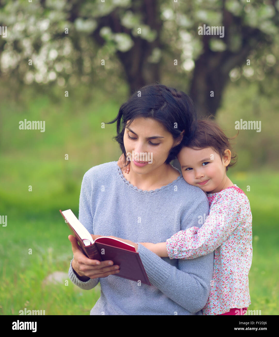 Madre e figlia di leggere un libro sul prato Foto Stock