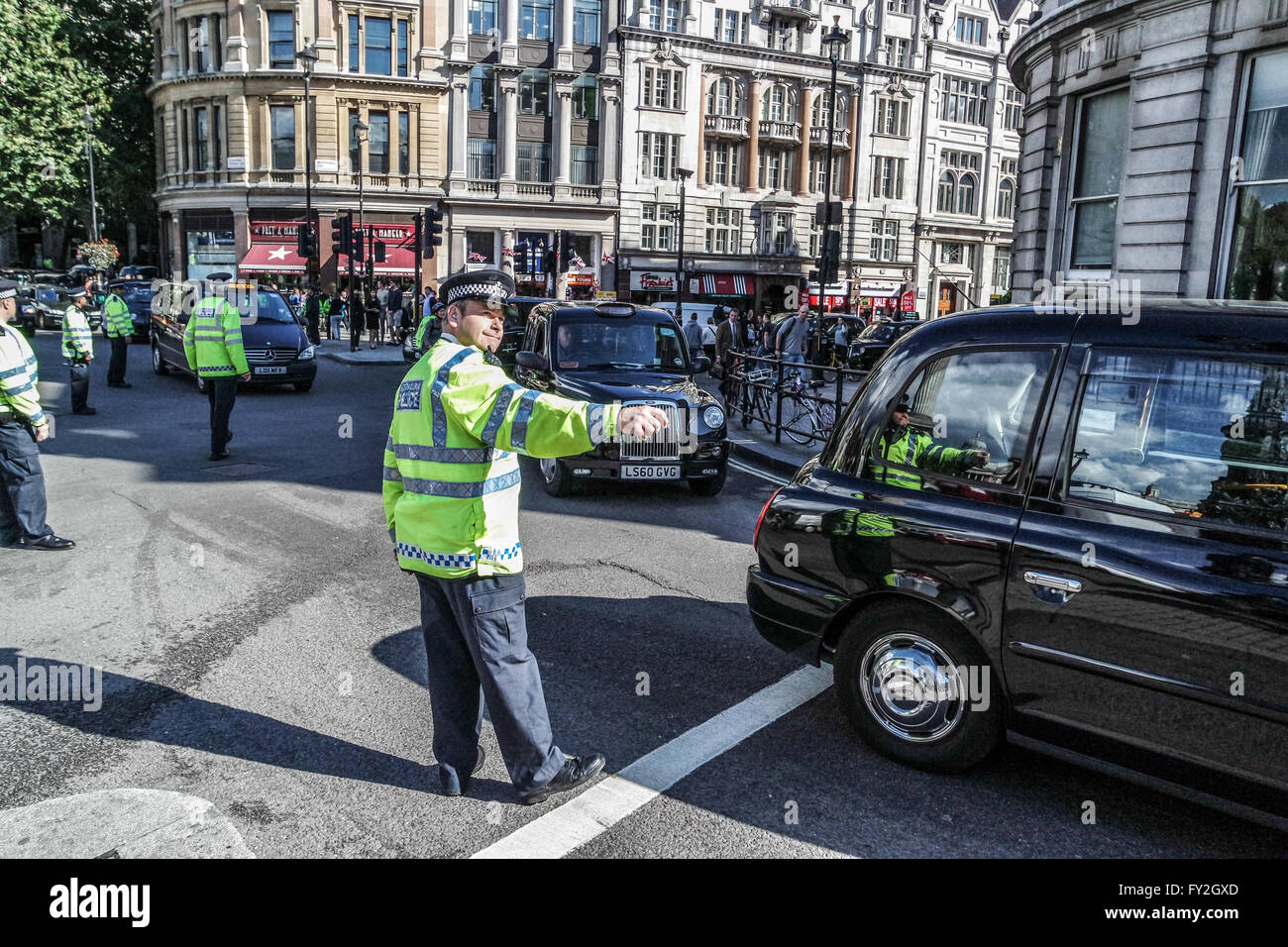 La polizia di Londra il traffico diretto e London Black taxi vicino a Trafalgar Square Foto Stock