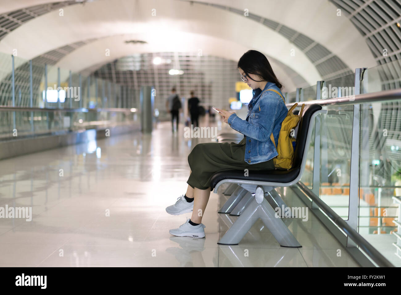 Donna asiatica traveler utilizzando smart phone, in attesa di imbarco in aeroporto del terminale Foto Stock