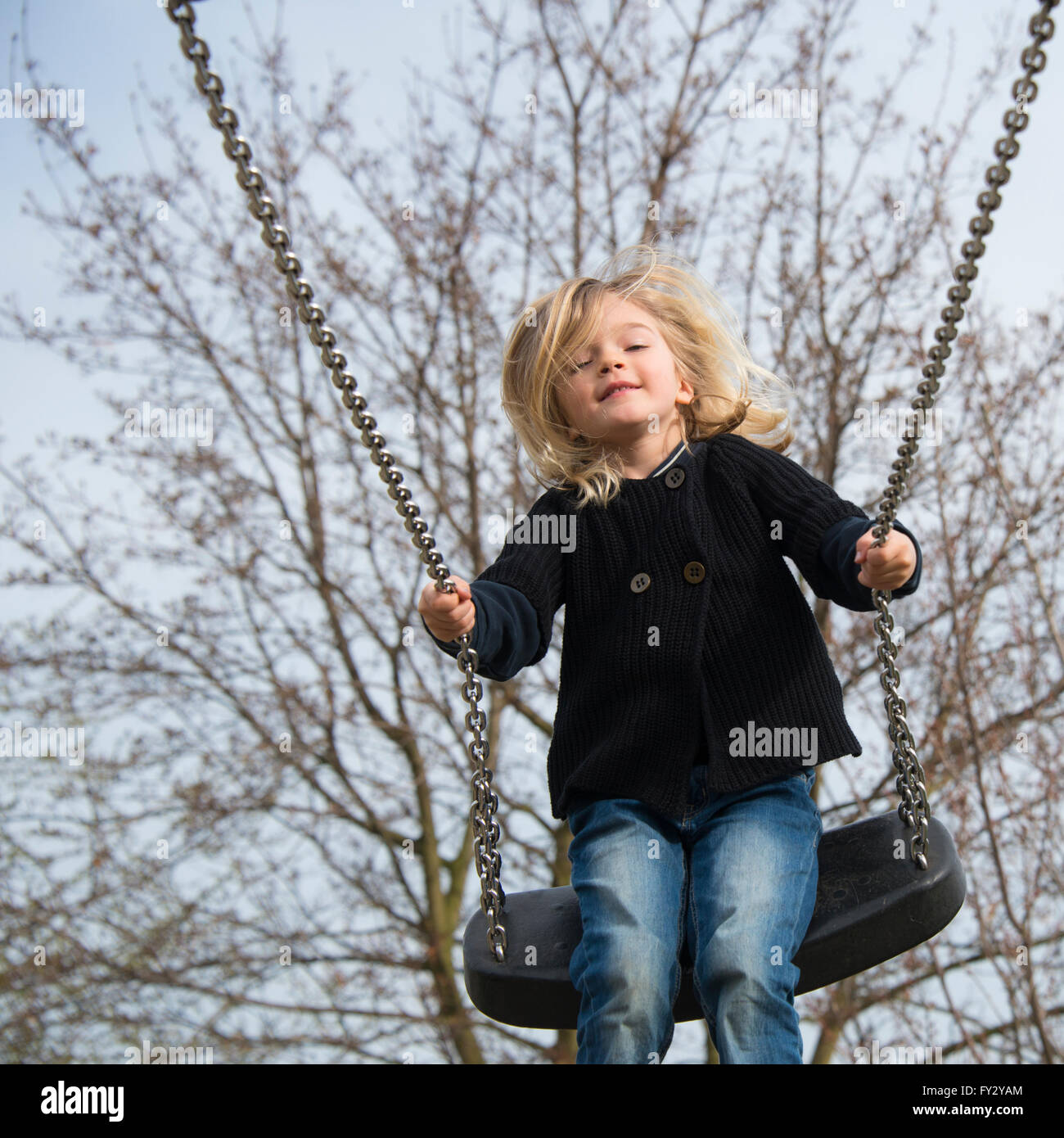 Bambino ragazza bionda divertirsi su altalena per esterno. Parco giochi estivo. Ragazza alta oscillante Foto Stock