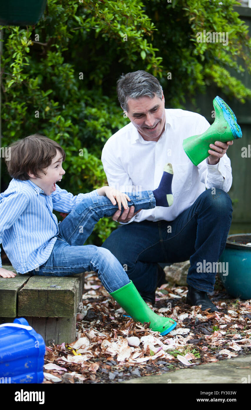 Papà lo svuotamento di boot per suo figlio Foto Stock