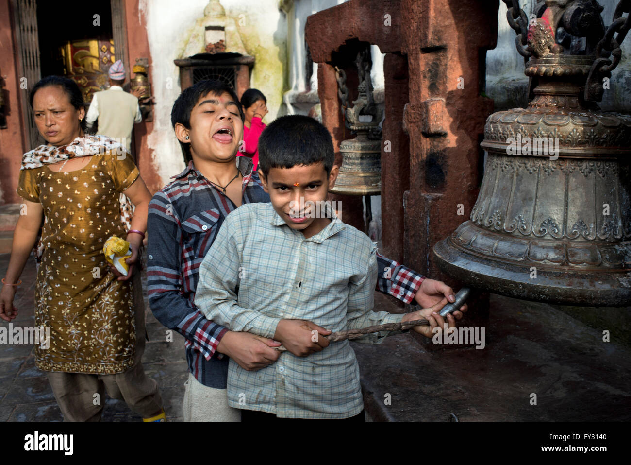 Bambini squillo campana gigante per celebrare il periodo del nuovo anno tibetano a Stupa Boudhanath, Kathmandu, Nepal. Foto Stock