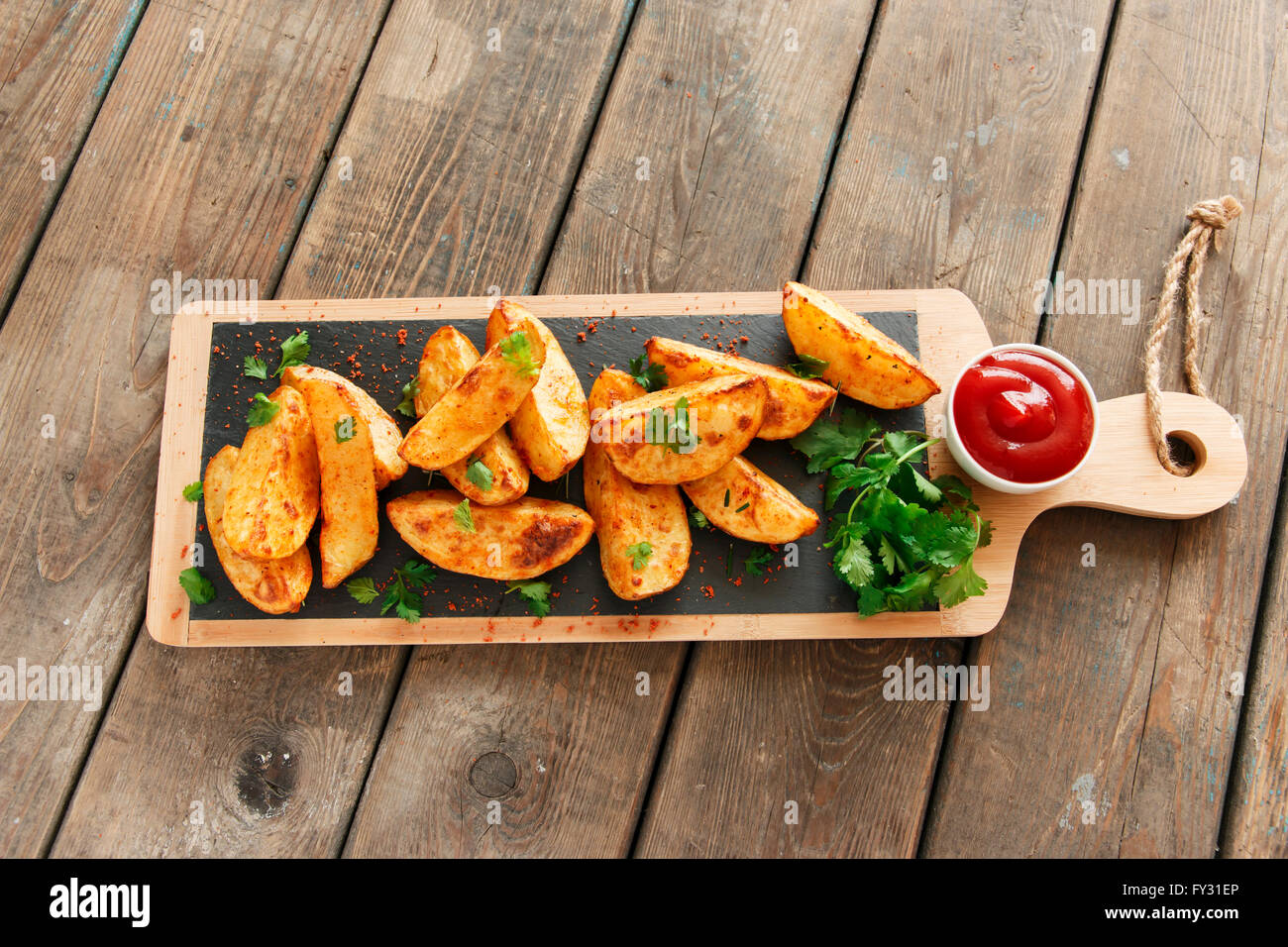 Cotto arrosto Spicchi di patate con erbe aromatiche Foto Stock