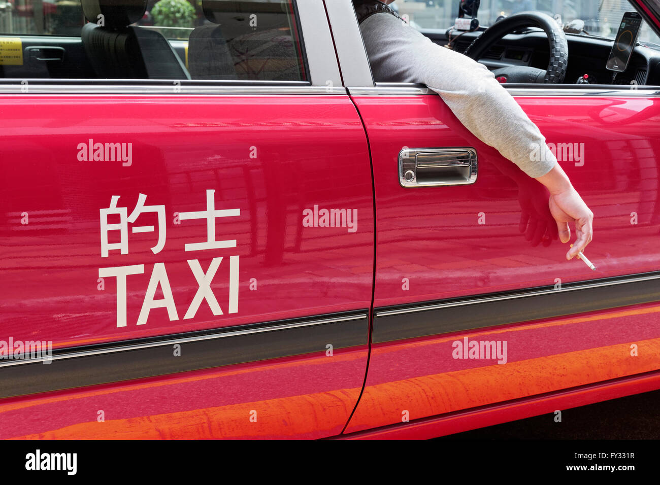 Red Hong Kong taxi, ruota sul lato destro, driver la mano con la sigaretta fuori dalla finestra, Hong Kong, Cina Foto Stock