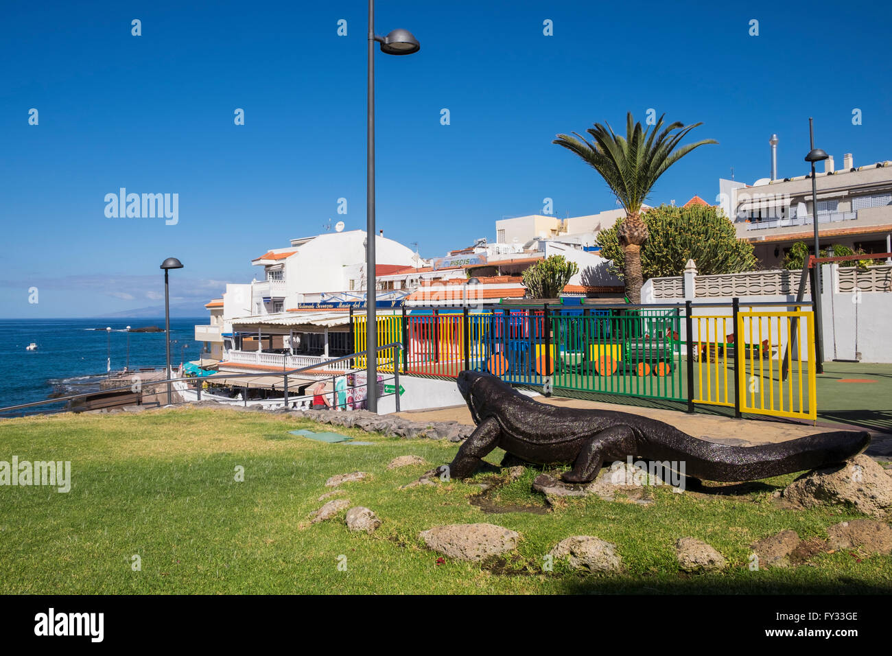 Lucertola gigante scultura sull'erba vicino alla zona ristorante nel villaggio costiero di La Caleta, Costa Adeje, Tenerife, Canarie Foto Stock