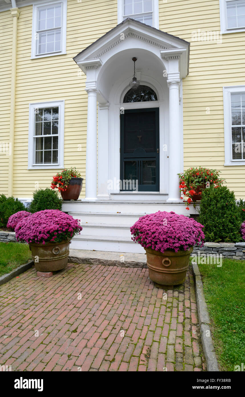 Giallo multi-storia di una casa con un portico, marciapiede di mattoni e fiori  con fiori di colore rosa Foto stock - Alamy