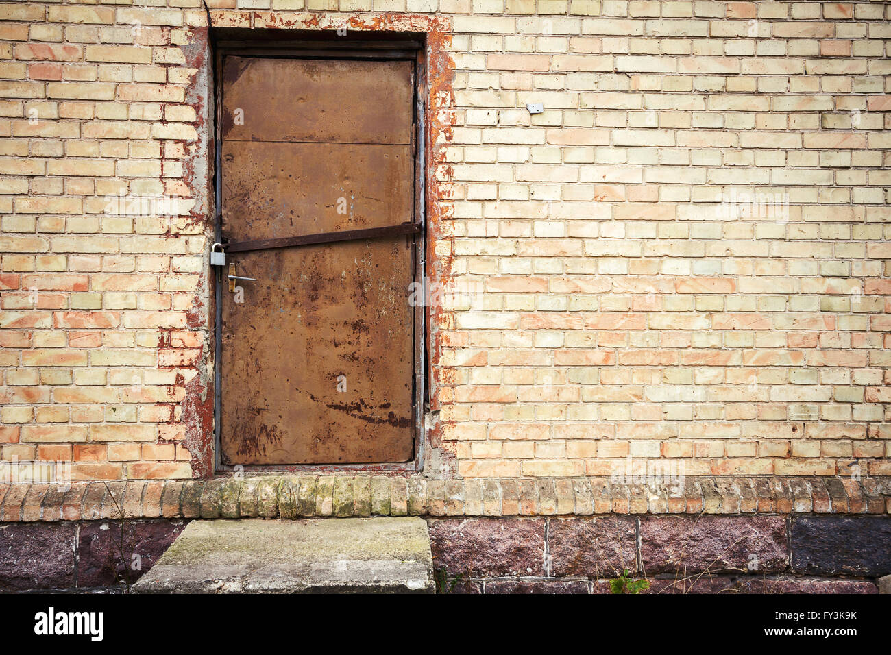 Vecchia porta di ferro in un giallo parete di mattoni Foto Stock