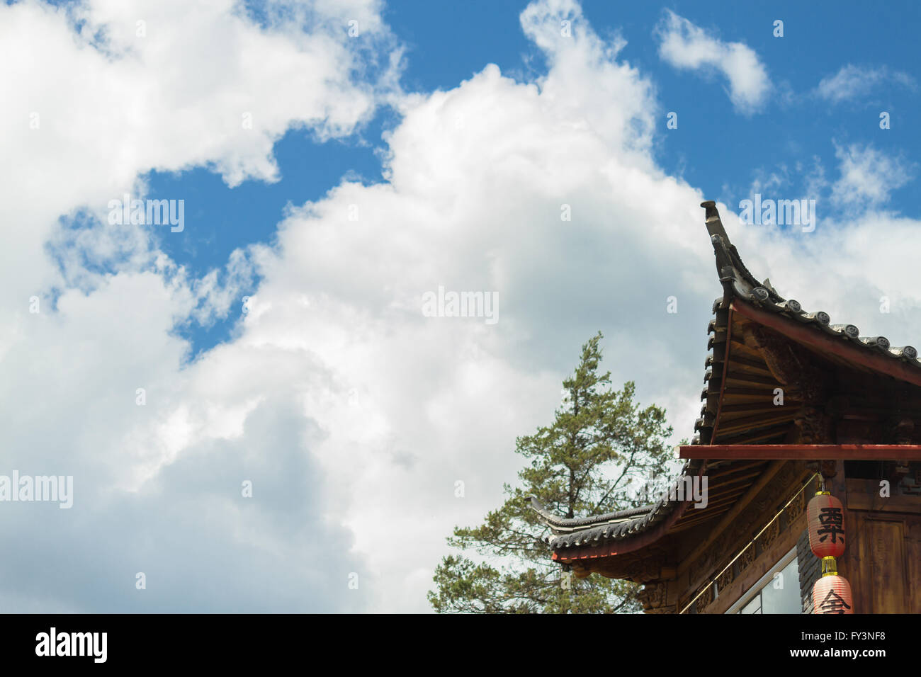 Cinese tradizionale tetto curvo (spazzamento curvatura) con lanterne rosse contro il cielo nuvoloso della provincia dello Yunnan Foto Stock