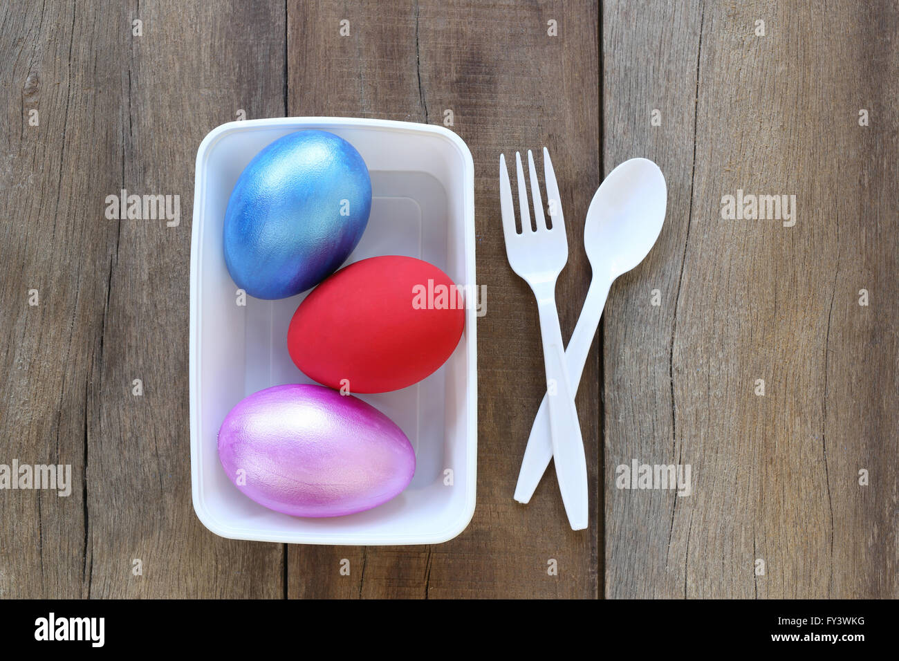 Uovo di Pasqua con una varietà di colori nel recipiente di plastica e hanno cucchiaio,forcella sullo sfondo di legno vecchio. Foto Stock