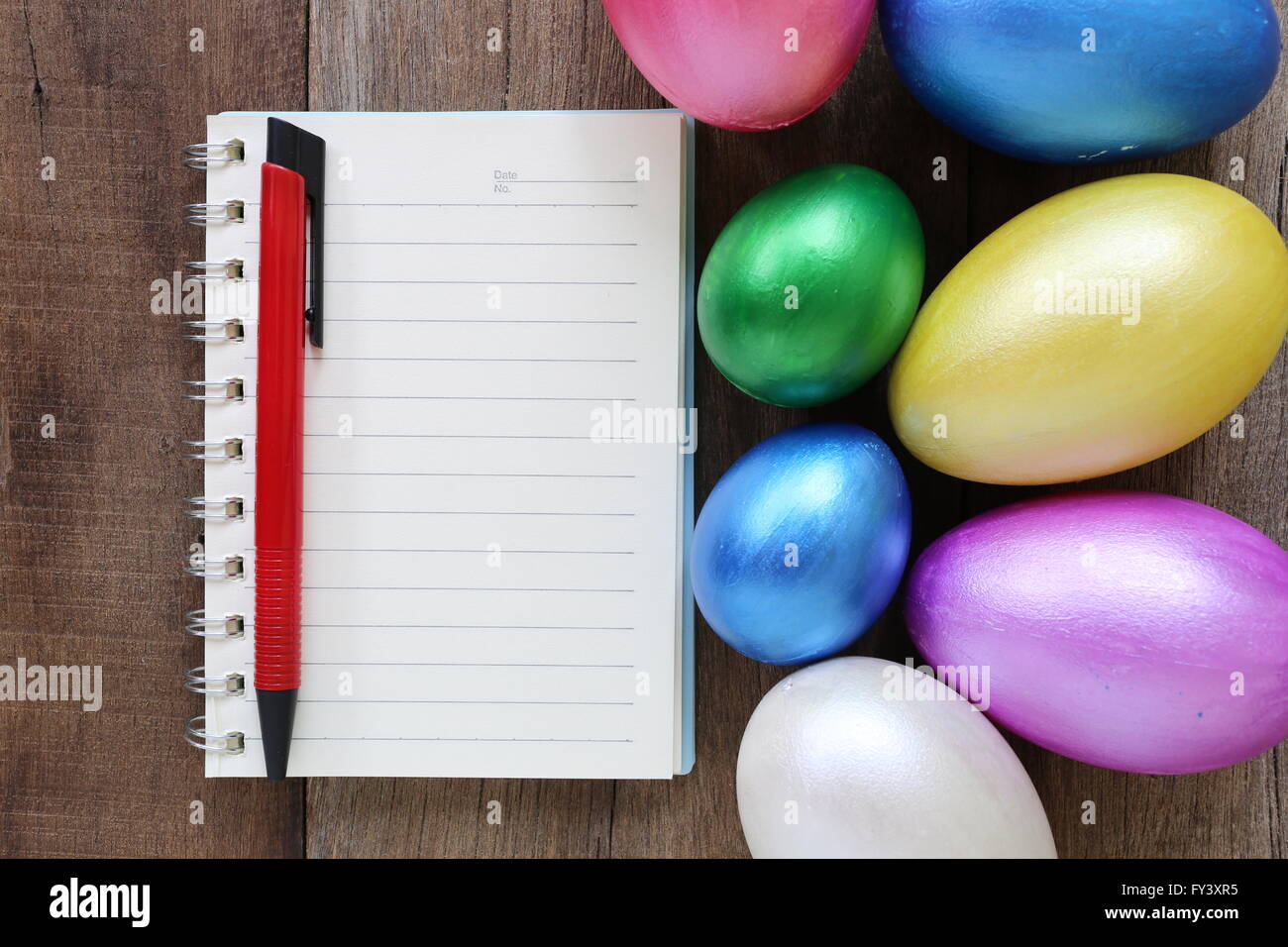 Uova di Pasqua e note book su uno sfondo di legno,dipinte a mano per la progettazione felice giorno di Pasqua. Foto Stock