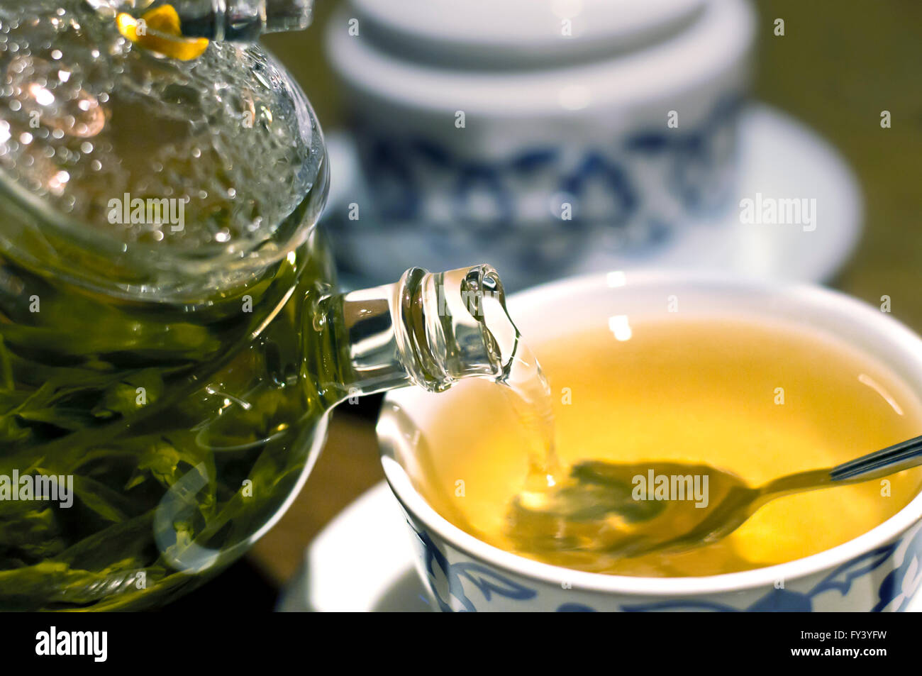 Teiera di vetro versando il tè verde in una tazza Foto Stock