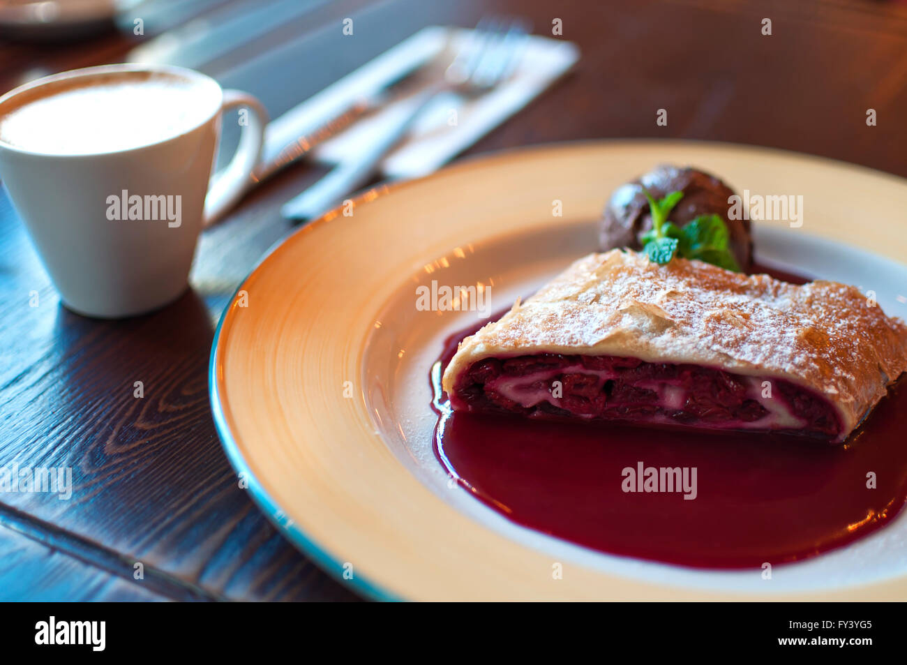 Piastra di strudel di ciliegie e la tazza di caffè in una tabella Foto Stock