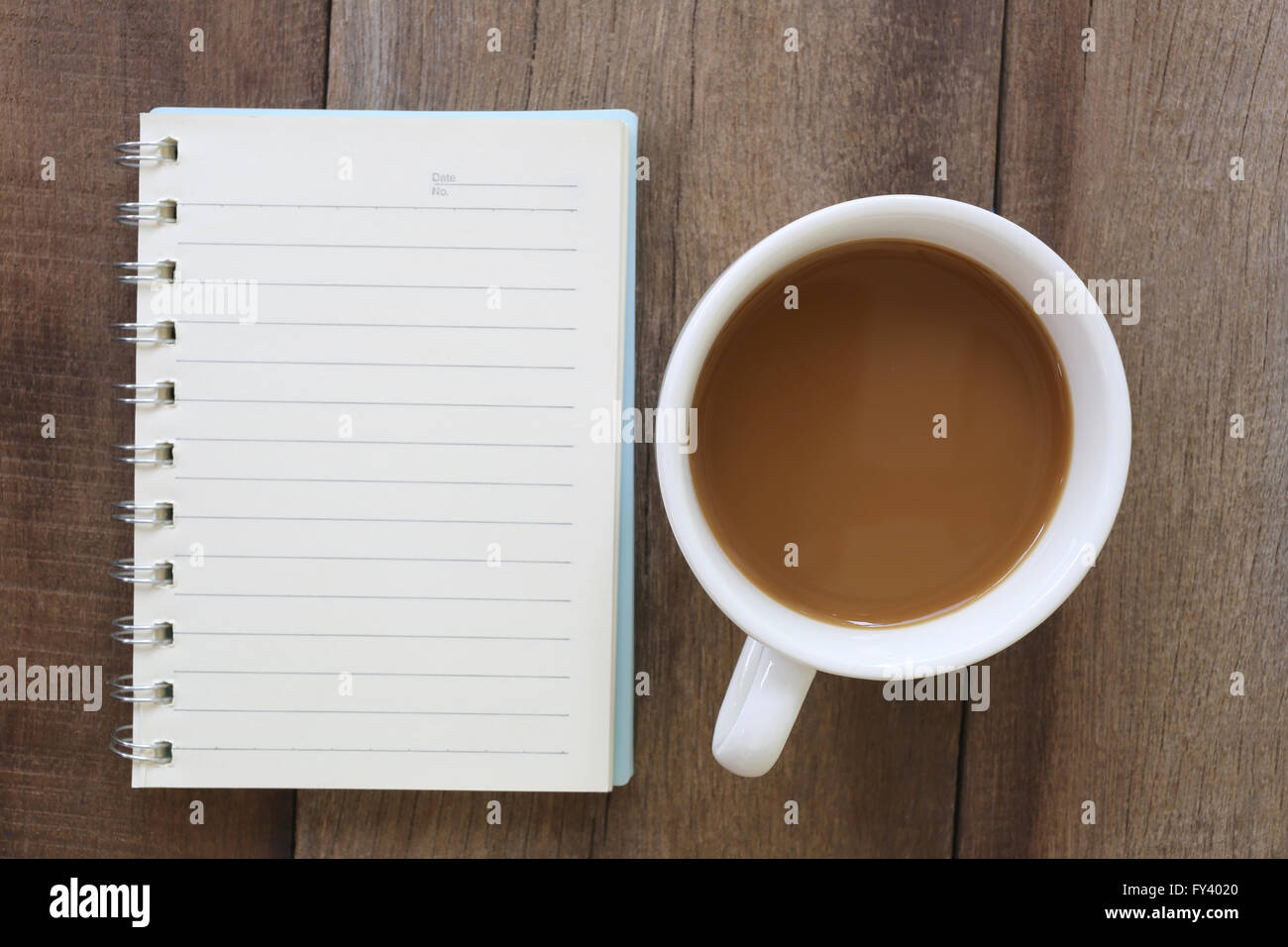 White tazza di caffè e notebook posizionato sul vecchio pavimento in legno,Design per circa caffeina bere. Foto Stock