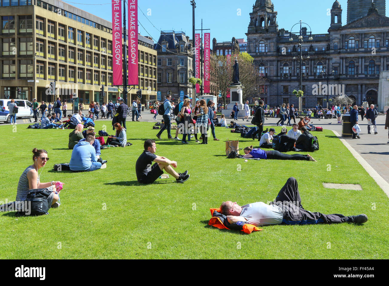 Molte persone, i turisti e gli impiegati hanno approfittato del caldo e soleggiato, molla meteo avendo pranzo e relax in George Square, Glasgow city centre Foto Stock