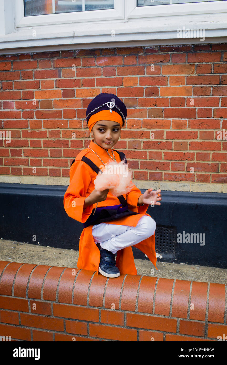 Un piccolo ragazzo mangia Candy Floss nella sua tuta sfilata in attesa per l'inizio delle celebrazioni Vaisakhi in Southampton (UK) Foto Stock