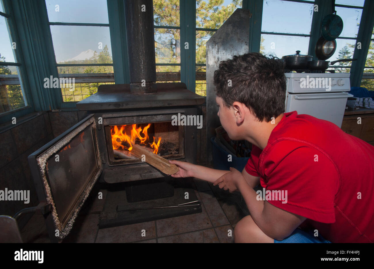 12 anno vecchio ragazzo woodstove alimentazione, cinque miglia di Butte Lookout, Mt. Cappa, Oregon Foto Stock