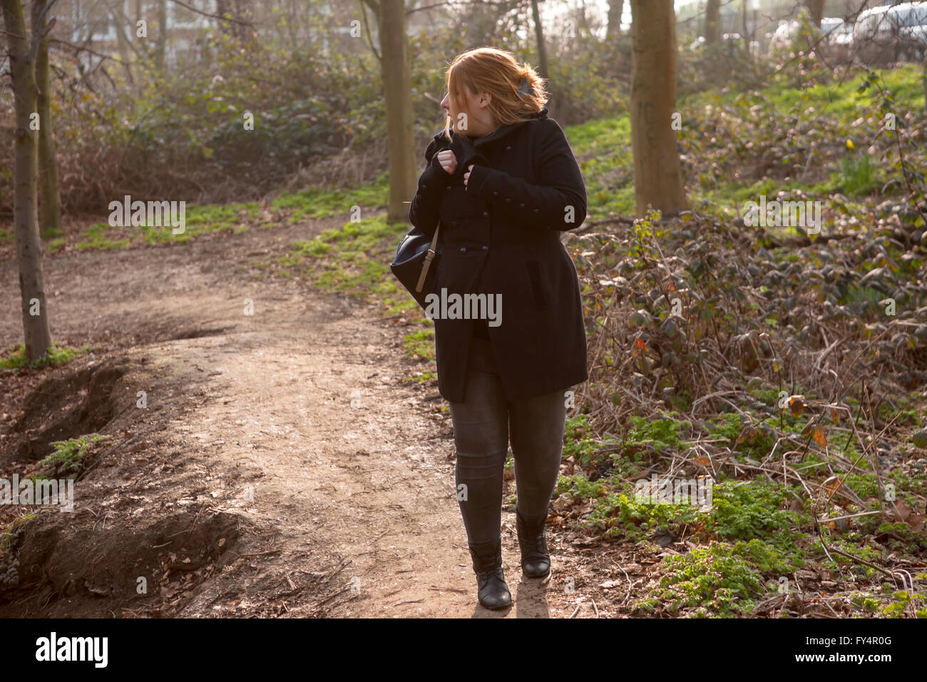 Una donna è a casa a piedi attraverso il parco e si sente certo vi è qualcuno dietro di lei. Foto Stock