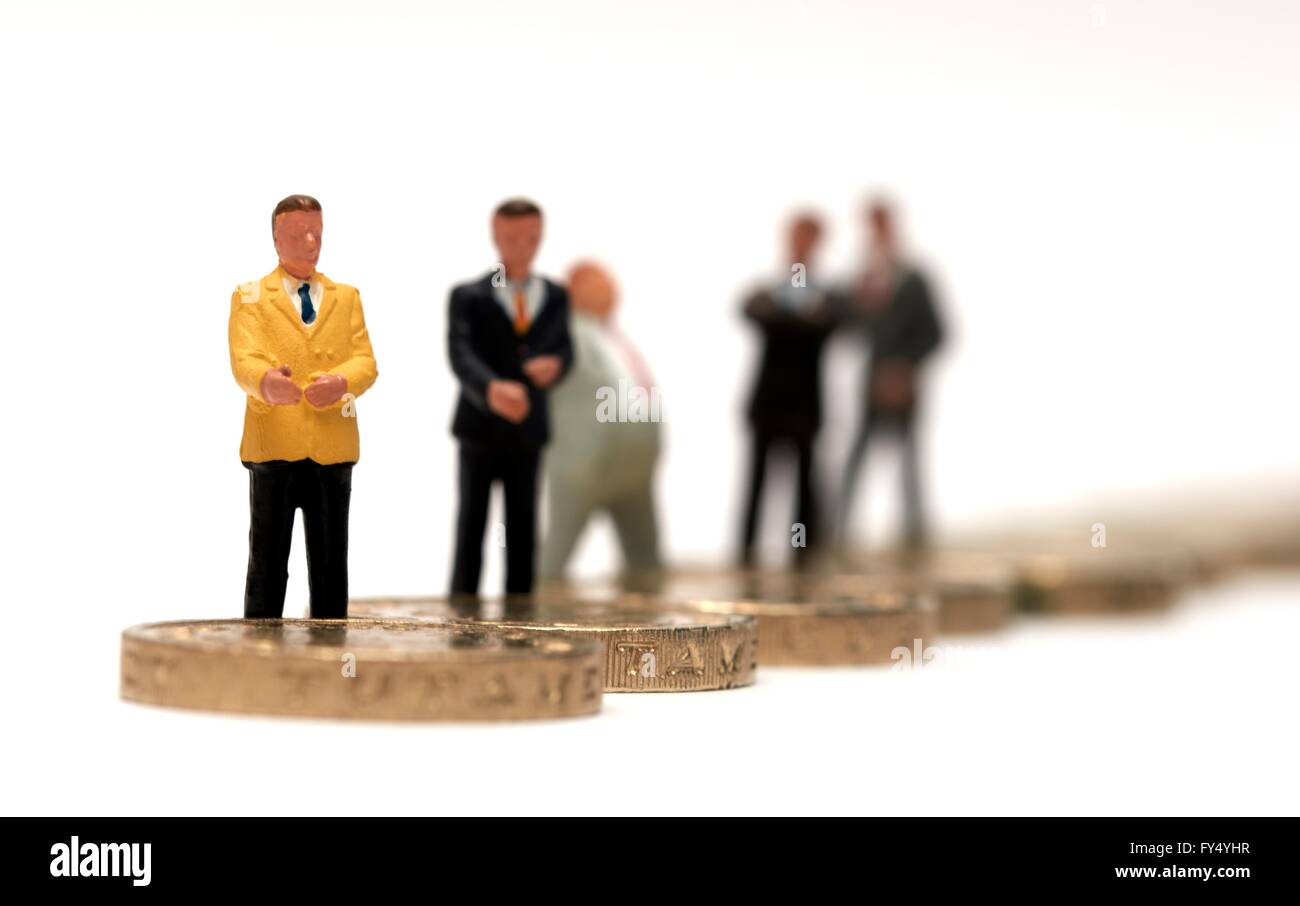 Un gruppo di figurine in miniatura di uomini di affari in piedi su alcuni britannici una libbra di monete Foto Stock