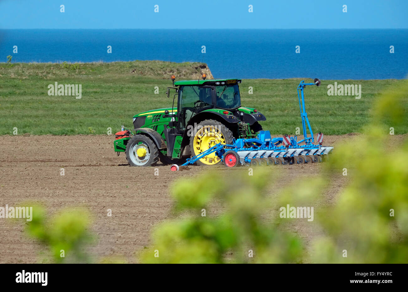 Il trattore e erpice a dischi sulla costiera di terra agricola, weybourne, North Norfolk, Inghilterra Foto Stock