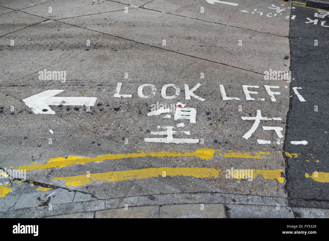 "Guardare a sinistra' segno dipinto sulla strada in inglese e cinese, informando i pedoni da quale lato il traffico su strada è venuta. Foto Stock
