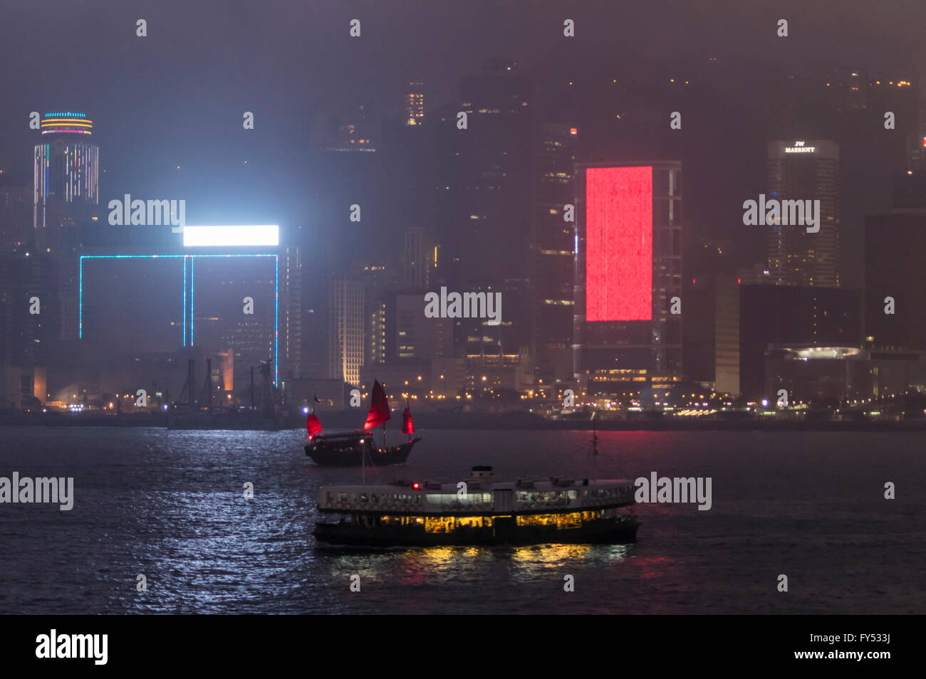 Un traghetto Star e junk attraversando il Victoria Harbour tra l'Isola di Hong Kong e Kowloon e di notte. Foto Stock