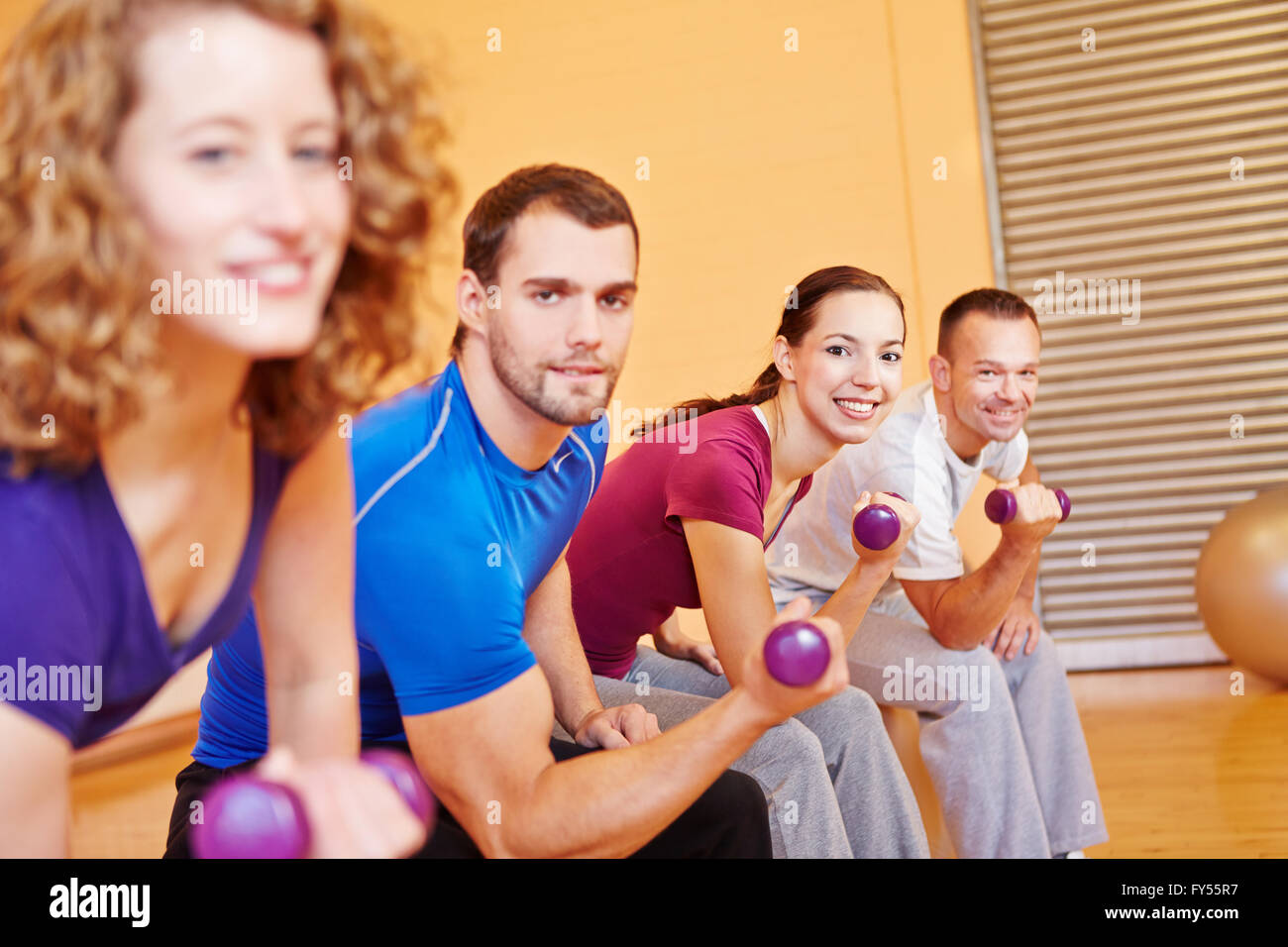 Gruppo felice esercitare insieme con manubri in centro fitness Foto Stock