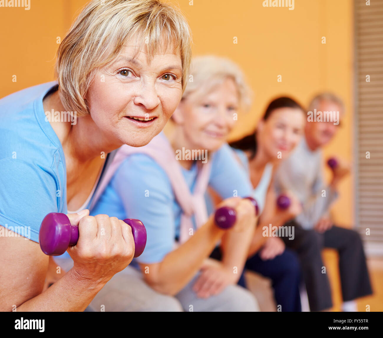 Donna senior con manubri facendo nuovamente la formazione in un centro fitness Foto Stock