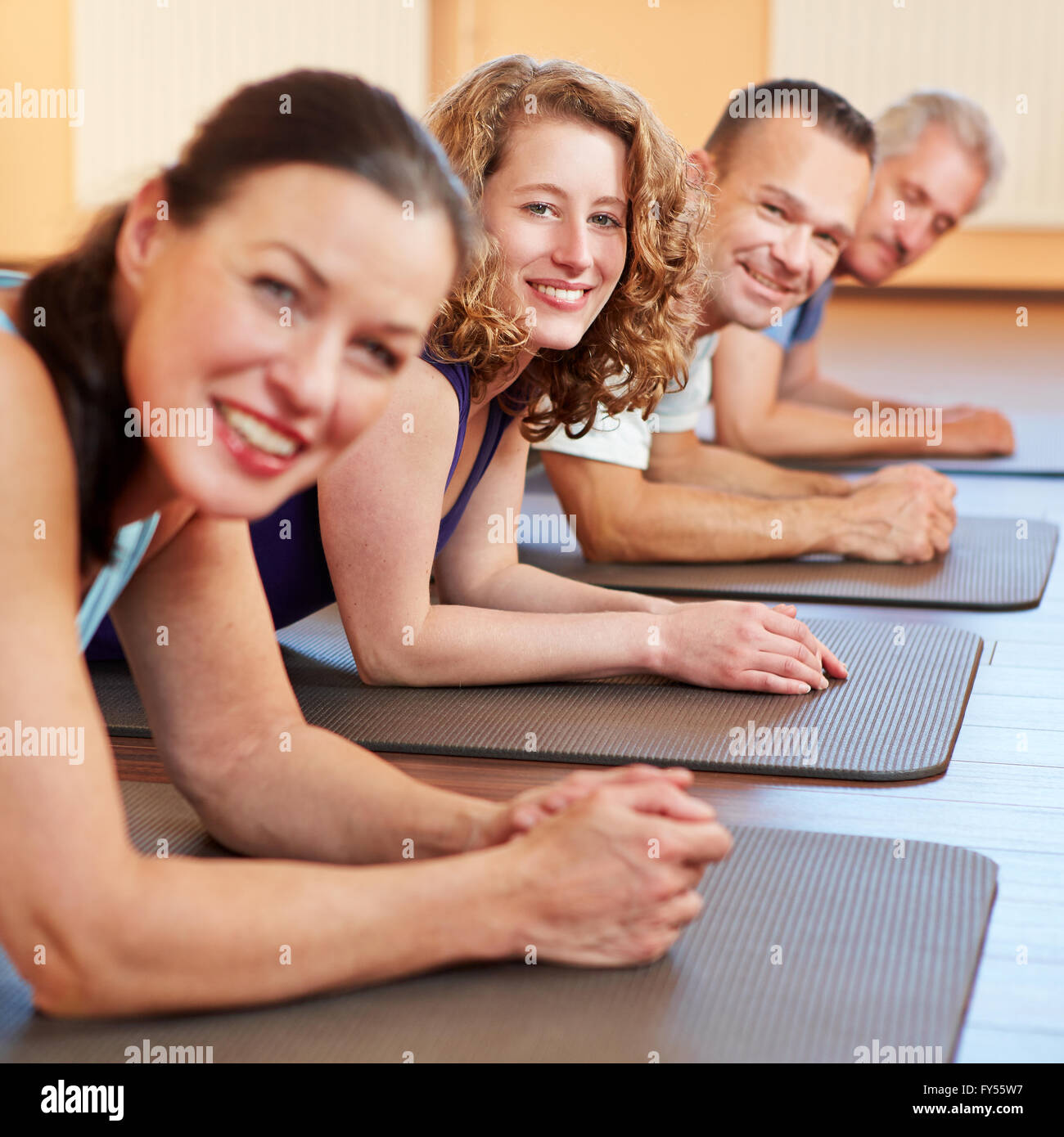 Felici gli uomini e la donna posa sorridente in palestra stuoie in un centro fitness Foto Stock
