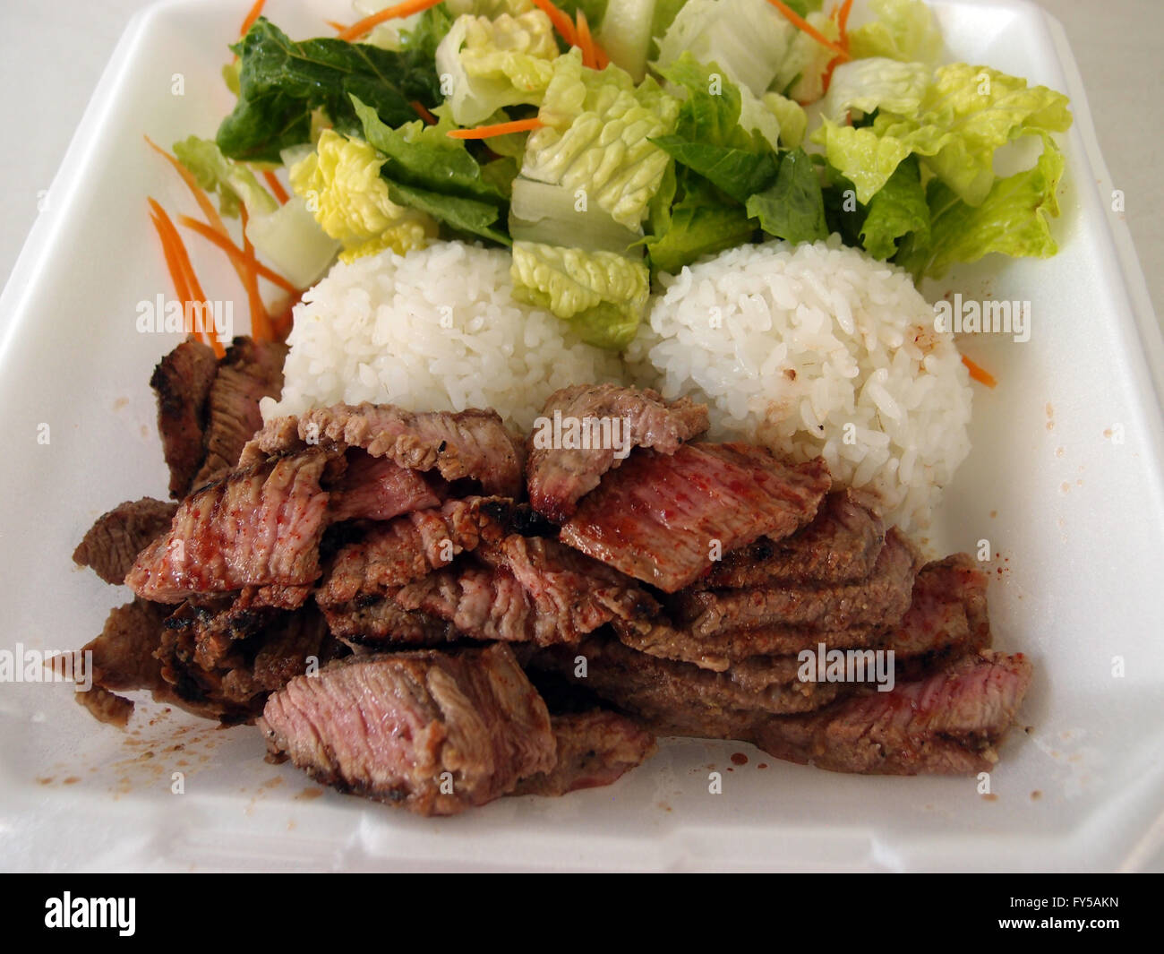 Raro medie bistecca tritata con spezie, riso bianco, mescolare insalata in una lastra di polistirolo hawaii locale la piastra di stile il pranzo. Foto Stock