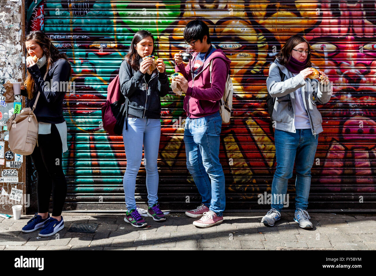 I giovani a mangiare cibo In Brick Lane, London, Regno Unito Foto Stock