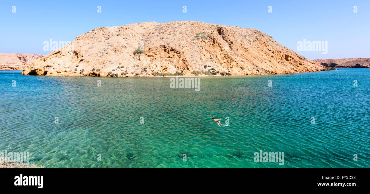 Donna che fa snorkeling in una spiaggia segreta in Oman, tra Mascate e Tiwi. Vista panoramica sul mare e la montagna sullo sfondo Foto Stock