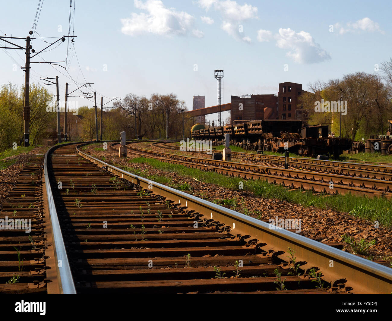 Piegare di multi-lane ferroviari con semaforo, piattaforma e carri cisterna e la miniera di ferro di edifici in background Foto Stock