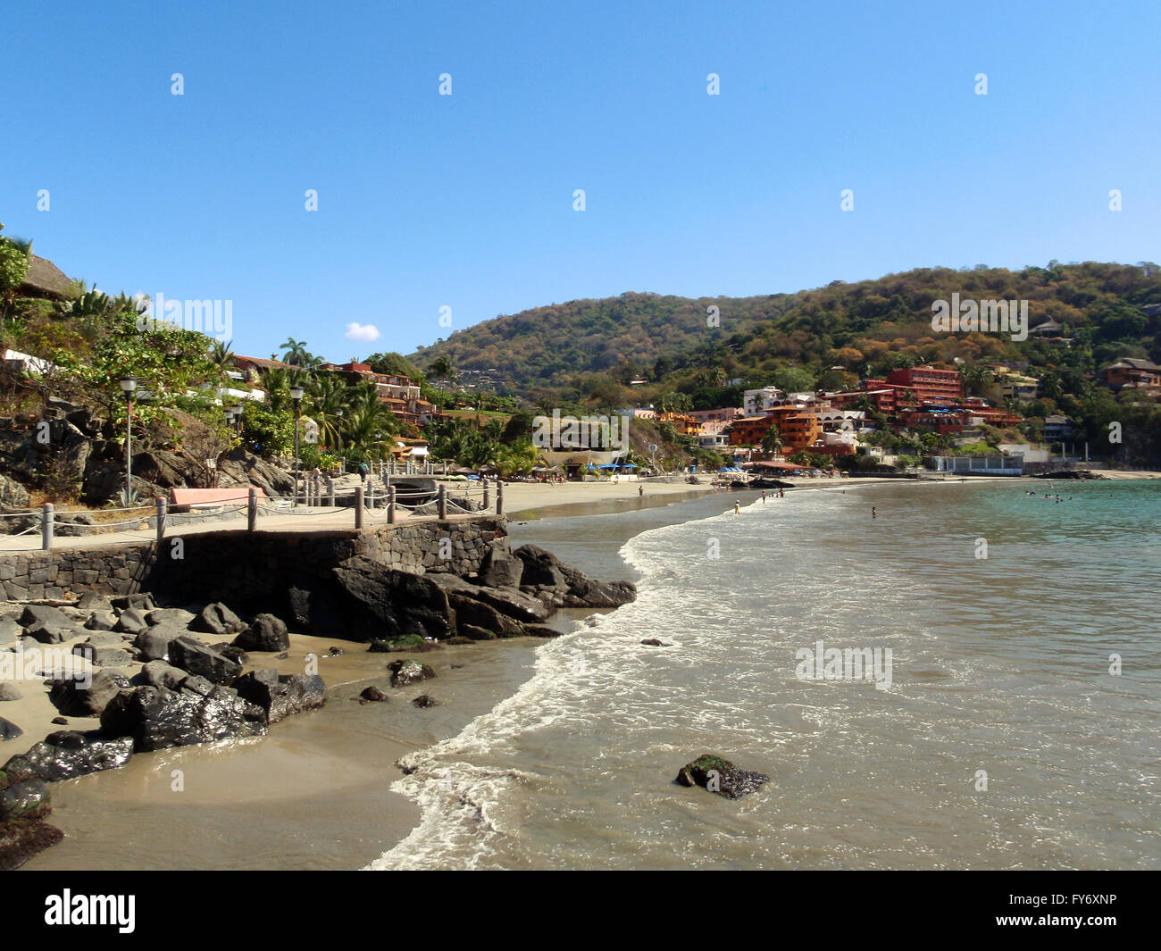 Persone giocare nella calma onde su una limpida giornata a Playa La Ropa Beach a Zihuatanejo Messico Foto Stock