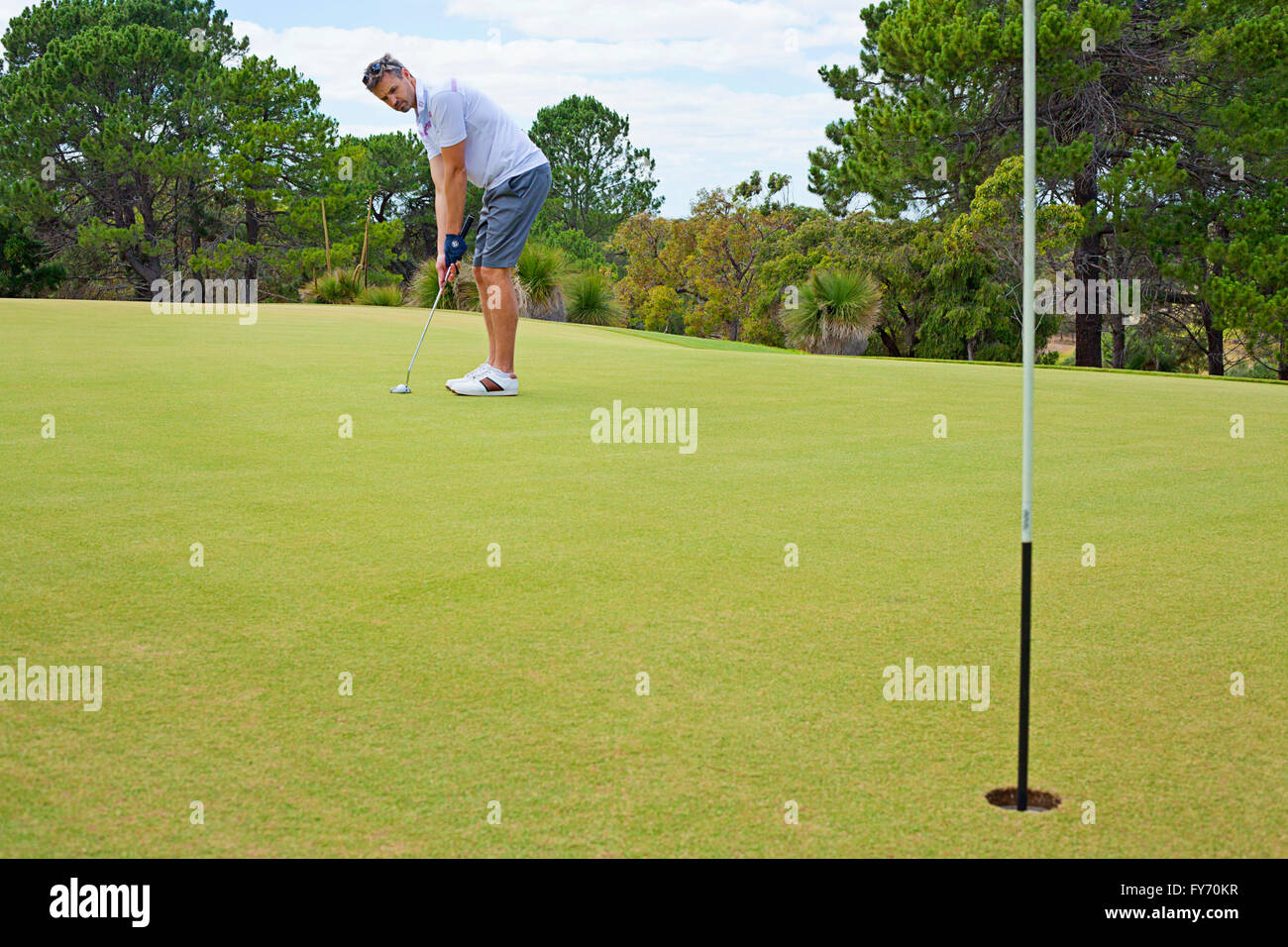 Giovane giocatore di golf putting verso il foro. Campo da golf. Foto Stock