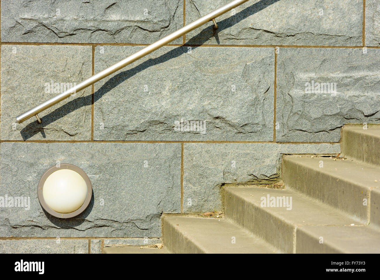 Grande pietra di granito blocchi su di un muro solido. Piccola lampada a parete e passi che conducono in alto o in basso nella parte anteriore di essa. Ringhiera in acciaio atta Foto Stock