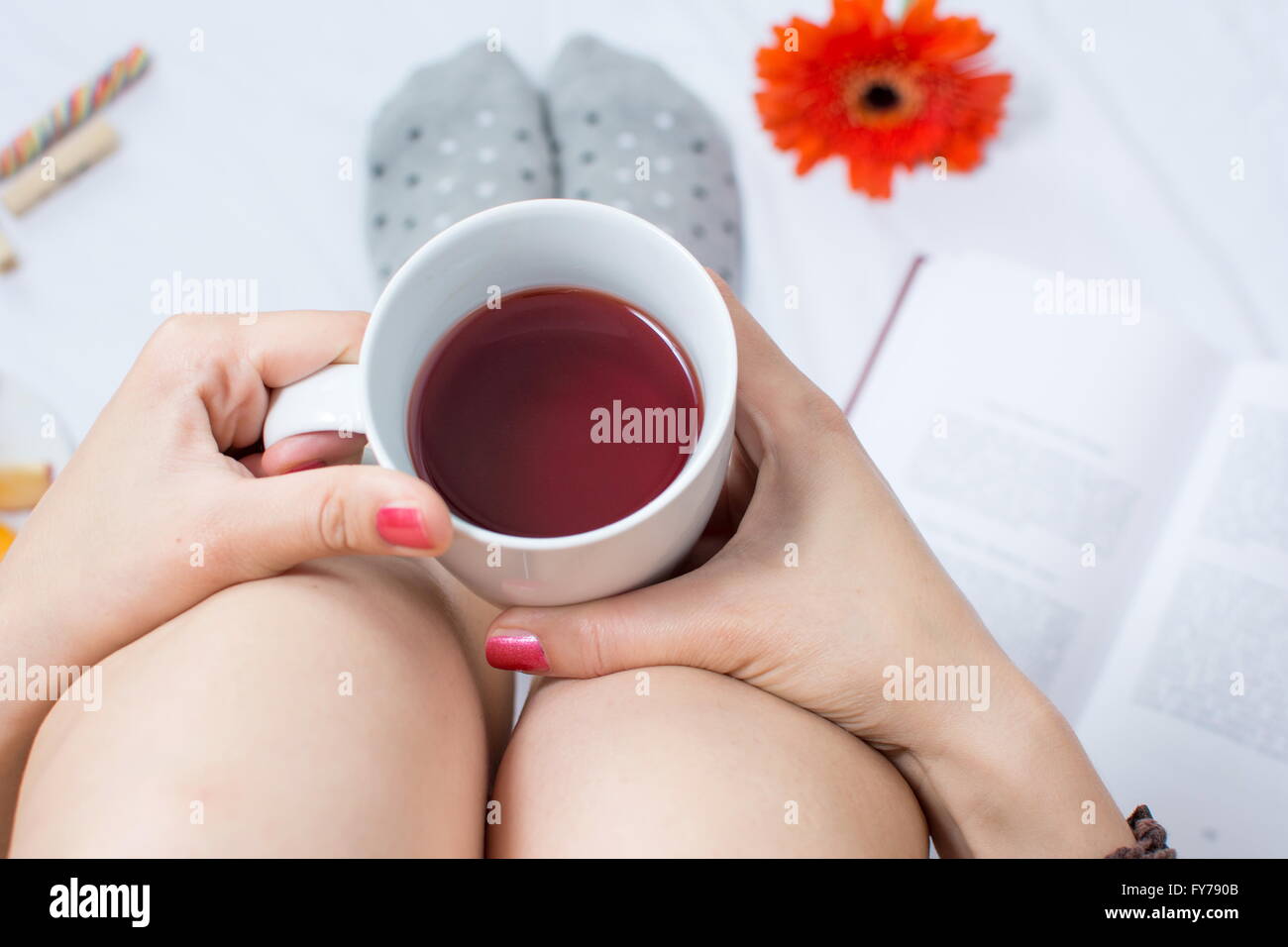 Donna che mantiene una tazza di tè nel letto Foto Stock