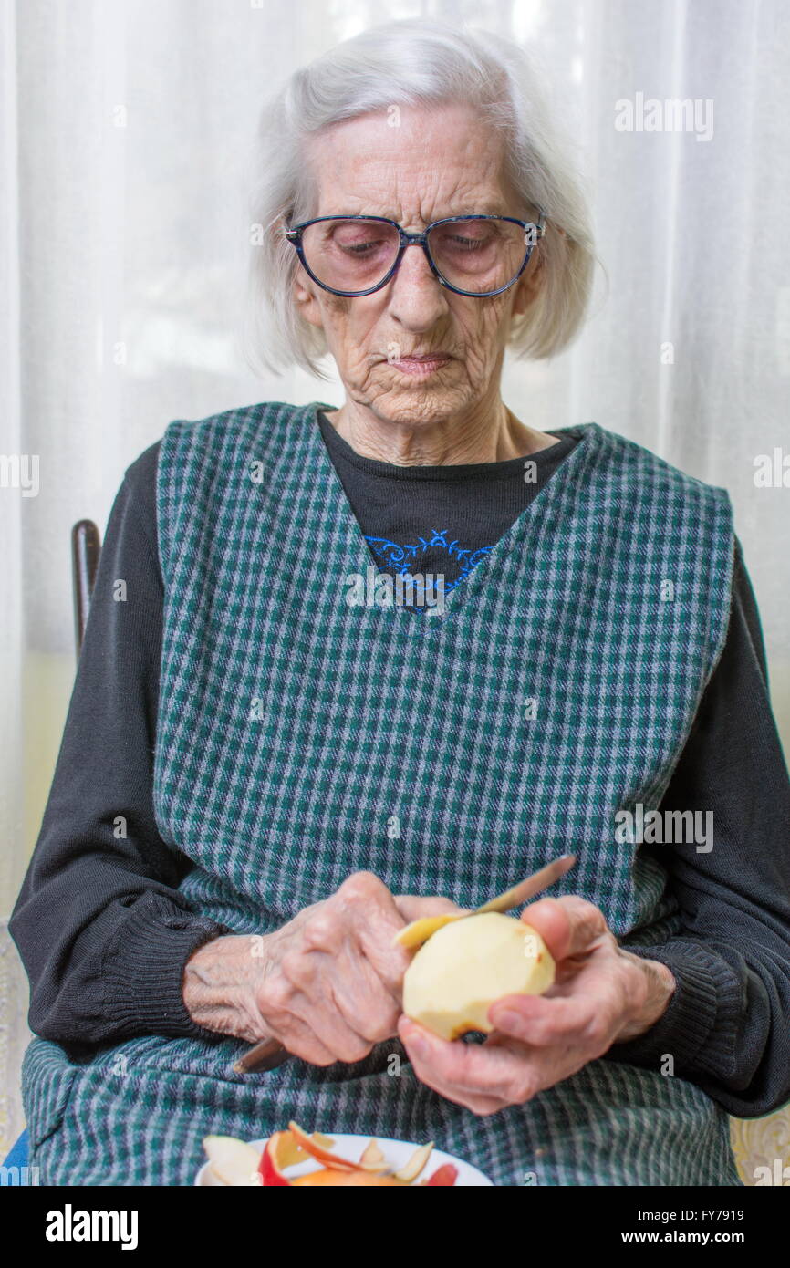 Novanta anni nonna la tranciatura e la sfogliatura di un Apple in ambienti interni Foto Stock