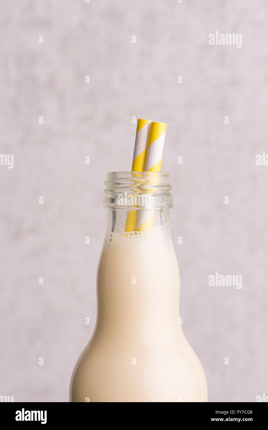 Il latte di soia in una bottiglia di vetro con striping cannucce potabile in stretta verso l'alto. Foto Stock