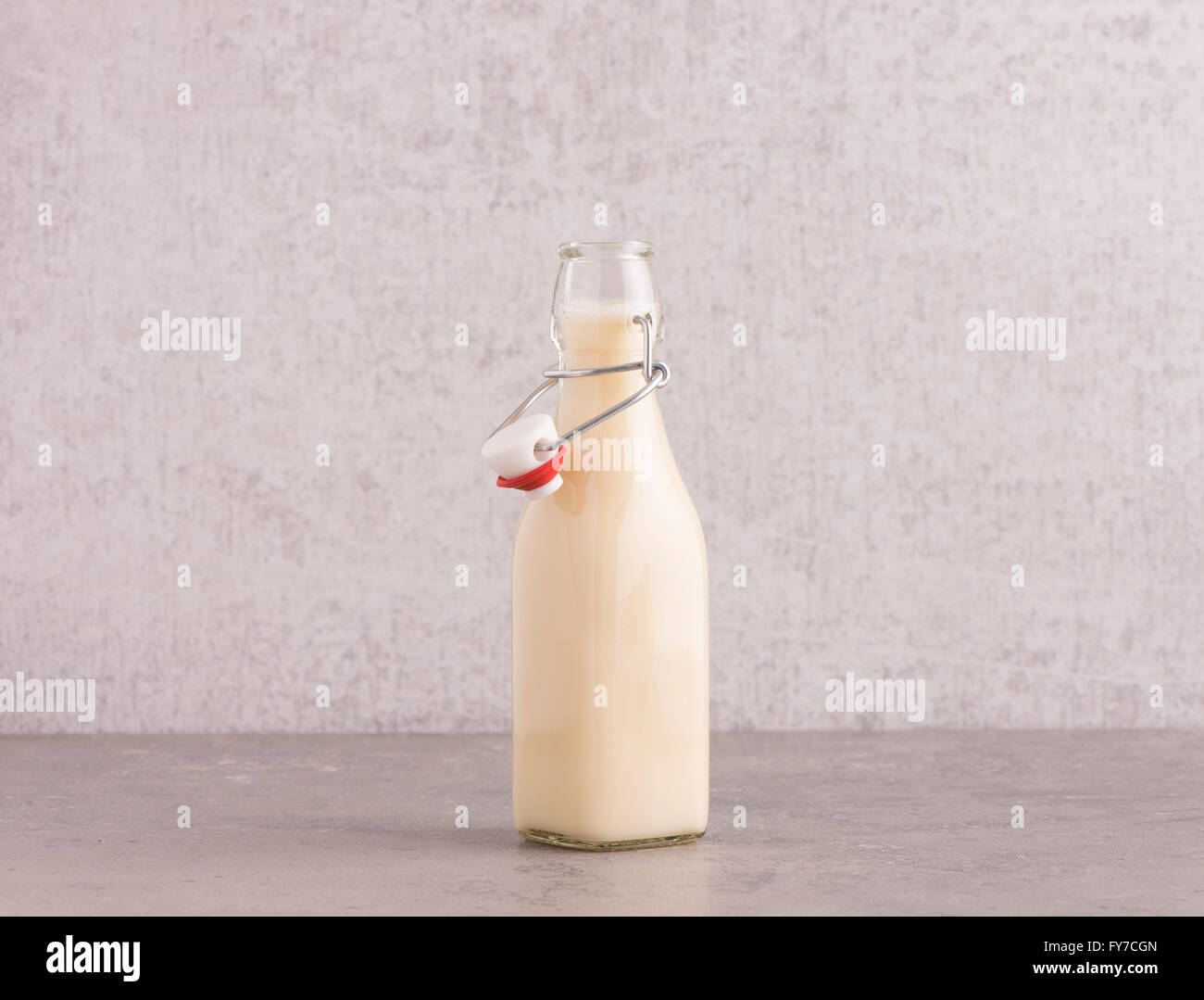 Latte di avena in una bottiglia di vetro sul tavolo da cucina. Muro di pietra con uno sfondo con spazio di copia. Foto Stock